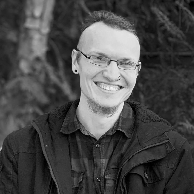 Eine schwarz-weiß Aufnahme von Jonas Goltz. Er trägt eine Brille und lächelt in die Kamera.